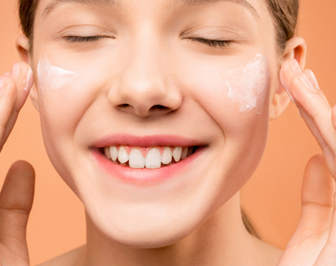 Girl applying skin lotion to her face